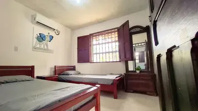 a bedroom with two beds and a mirror and a window at Casa Guadalupe Coveñas in Coveñas