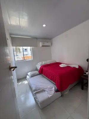 a small bedroom with a bed with a red blanket at Apartamento Caribe Coveñas 102 in Coveñas