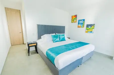 a bedroom with a large bed with blue pillows at Apto 1417 condominio Santa marina, Santa Marta in Estación El Salto