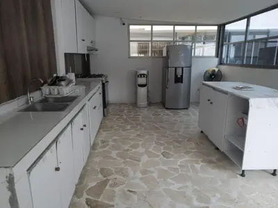a kitchen with white cabinets and a stone floor at Finca Villa Gabriela