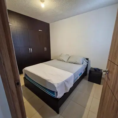 a small bedroom with a bed and wooden cabinets at Apartmento en Parque Heredia in Cartagena de Indias
