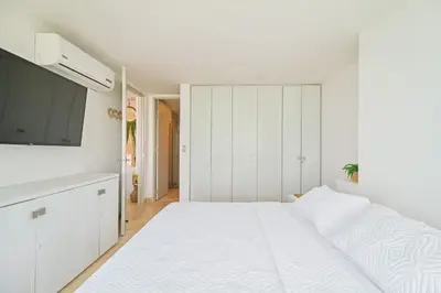 a white bedroom with a large bed and a flat screen tv at Sonesta Resort Apartamento Morros Cartagena in Cartagena de Indias