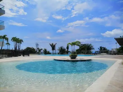 a swimming pool with blue water and palm trees at Sonesta Resort Apartamento Morros Cartagena in Cartagena de Indias