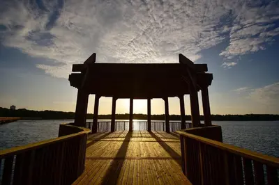a wooden dock with the sun shining on the water at Apartamentos Palmar - Excelente Ubicación by SOHO in Barranquilla