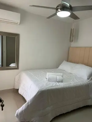 a white bed with a ceiling fan and a mirror at Apartamento Económico en Cartagena in Cartagena de Indias