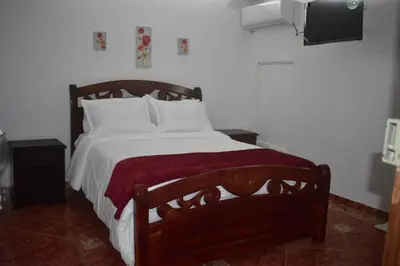 a bedroom with a bed with white sheets and a tv at Hotel San Francisco Inn in Barranquilla