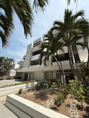 a building with palm trees in front of it at Barrio El Golf Apartment in Barranquilla