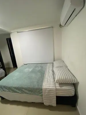 a bed in a room with a white wall at Cómodo & Económico Apartamento en La Boquilla Zona Norte Cartagena in Cartagena de Indias