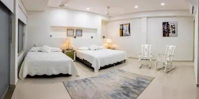 two beds in a white room with two chairs at Casa Romero Cartagena Casa de Playa in Cartagena de Indias