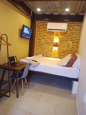 a room with a bed and a table and a laptop at Casa Pacoa in Cartagena de Indias