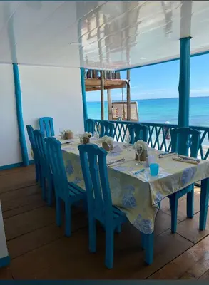 a table with blue chairs and the ocean in the background at Renacer ancestral Barú in Playa Blanca