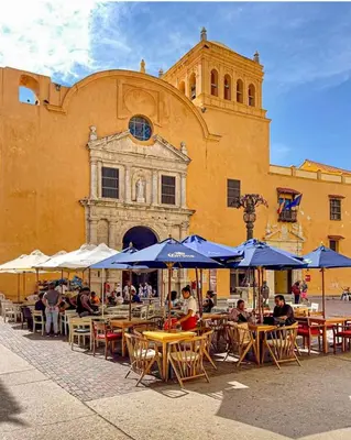 people sitting at tables with umbrellas in front of a building at Apto cuesta 203 in Cartagena de Indias