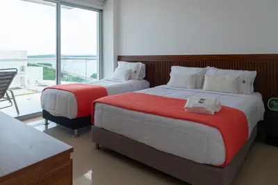 two beds in a room with a large window at The Beaches-Beachfront Retreat in Cartagena de Indias