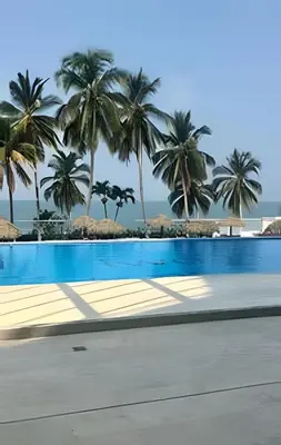a swimming pool with palm trees in the background at Wai Blue/Luxury Beachfront/ Bello Horizonte/ TTO03 in Playa Dormida