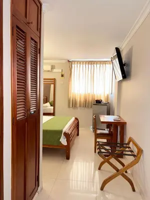 a bedroom with a bed and a table and a desk at Hotel San Francisco in Barranquilla