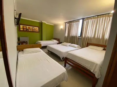 three beds in a room with green walls at Hotel San Francisco in Barranquilla