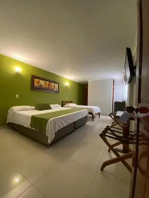 two beds in a room with green walls at Hotel San Francisco in Barranquilla