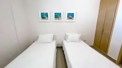 two beds in a room with three pictures on the wall at Magico Apartamento Frente al Mar 4 Habitaciones BM33 in Coveñitas