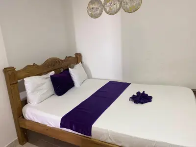 a bedroom with a bed with purple and white pillows at Apartamentos las palmas in Cartagena de Indias