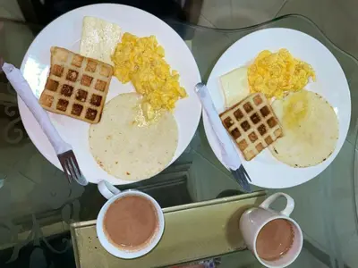 a table with plates of food and cups of coffee at Habitacion Pauvemar en Coveñas in Coveñas