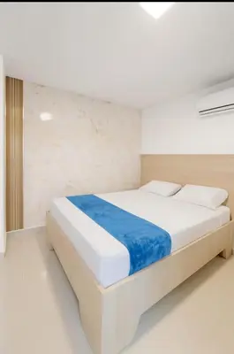 a bedroom with a large white bed with blue sheets at Apartamentos CP in Barranquilla