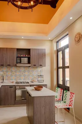 a kitchen with wooden cabinets and a counter with chairs at Casa Maguey – Refugio Tropical en el Centro de Cartagena in Cartagena de Indias