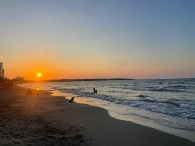 a sunset on the beach with people in the water at Villa Ana tu hogar lejos de casa in Coveñas