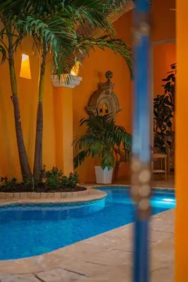 a pool with palm trees and a clock in a building at Niña Maria pool House Plaza San Diego, Downtown! in Cartagena de Indias
