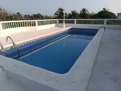 a swimming pool with blue water and a fence at La Trinidad in Santa Veronica
