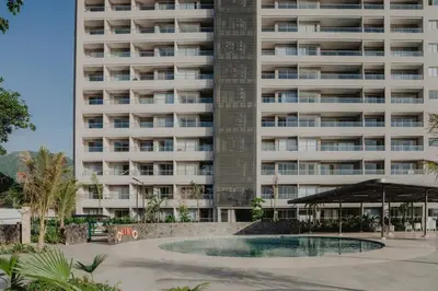 an apartment building with a pool in front of it at Coastal Comfort Retreat Beach stay Near Airport in Santa Marta