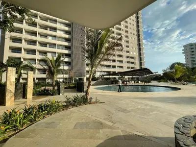 a large apartment building with a pool and a palm tree at Apartamento Playa y piscina, Santa Marta in Santa Marta