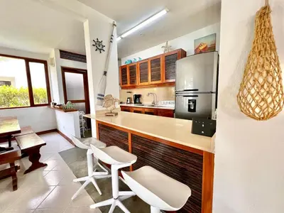 a kitchen with a counter and some white chairs at Hermosa villa frente al mar in San Silvestre