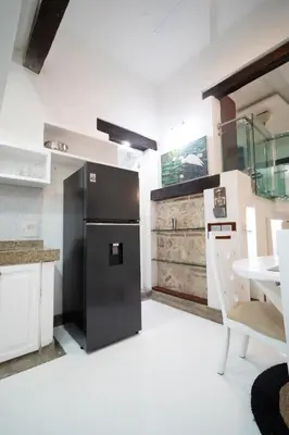 a kitchen with a black refrigerator and a table at Alma Blanca - Colonial Loft in the Walled City in Cartagena de Indias
