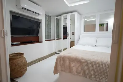a white bedroom with a bed and a flat screen tv at Alma Blanca - Colonial Loft in the Walled City in Cartagena de Indias