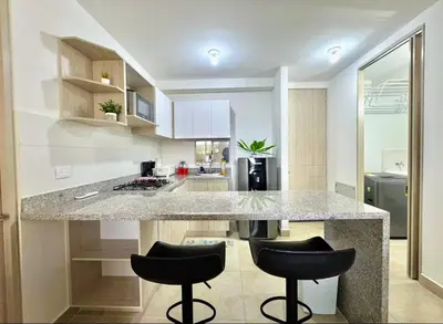 a kitchen with a large counter with two black bar stools at Lindo apartamento a 5 minutos del mar!!! in Manzanillo del Mar