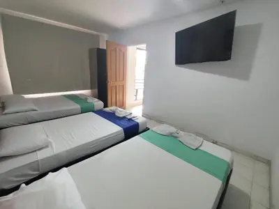 a room with two beds and a flat screen tv at Hotel Madeleine Norte in Barranquilla