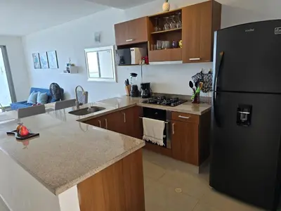 a kitchen with a black refrigerator and wooden cabinets at Ikigai frente al mar con piscina infinita y Gym in Cartagena de Indias