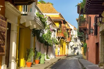 a narrow street with yellow and white buildings at City Tour por Cartagena con entradas in Cartagena de Indias