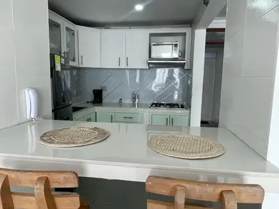 a kitchen with white cabinets and a counter with two chairs at Ocean view apartment in a great location in Cartagena de Indias