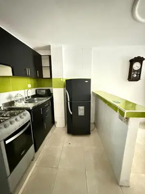 a small kitchen with a black refrigerator in it at First floor house in Barranquilla