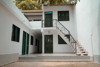 a white building with green doors and stairs at Cabaña las Palmas Rincon del Mar in Rincón