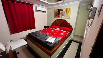 a small room with a bed with red roses on it at Hotel By Hours Jurassic in Barranquilla