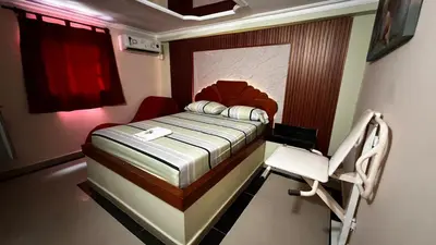 a small bedroom with a bed and a chair at Hotel By Hours Jurassic in Barranquilla
