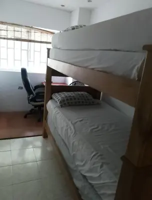 two bunk beds in a room with a chair at Alto prado 75 house in Barranquilla