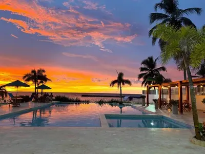 a resort swimming pool with a sunset in the background at Apartamento con vistas al Mar caribe in Coveñas