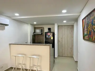 a kitchen with a counter with stools and a refrigerator at Ocean Drive Cartagena Apto con Piscina Infinity in Cartagena de Indias