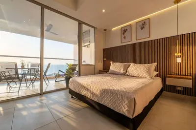a bedroom with a large bed and a balcony at Maravillosa suite frente al mar y atardecer CB911 in Cartagena de Indias
