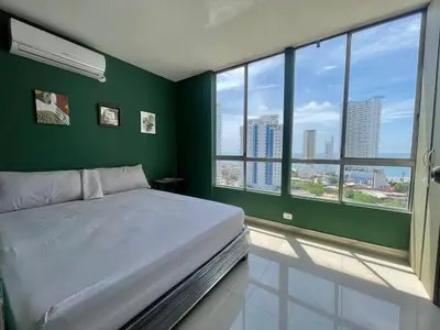 a bedroom with a bed with green walls and windows at Sea view apartment in Cartagena de Indias