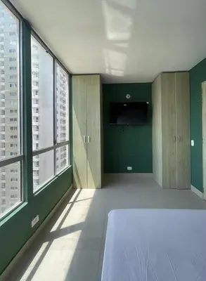 a room with green walls and a bed and windows at Sea view apartment in Cartagena de Indias