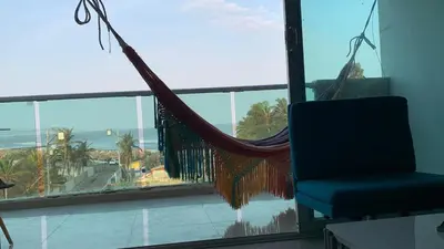 a hammock in a room with a view of the ocean at SUNSET LATITUDE, Apto frente al mar con hamaca y piscina in Puerto Colombia